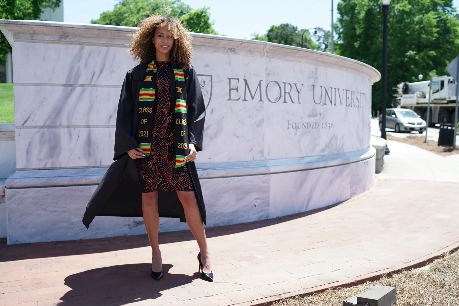 Claire Ofotokun (COFO) in graduation attire beside the Emory University sign, Class of 2021; photography and retouching by Gabriel Daniels.