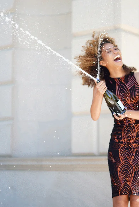 Claire Ofotokun (COFO) celebrating as a bottle sprays across the graduation portrait frame.