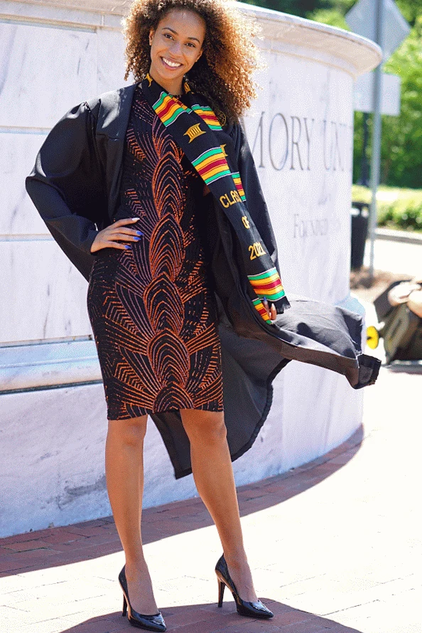 Claire Ofotokun (COFO) wearing a graduation gown and Class of 2021 stole beside an Emory University monument.