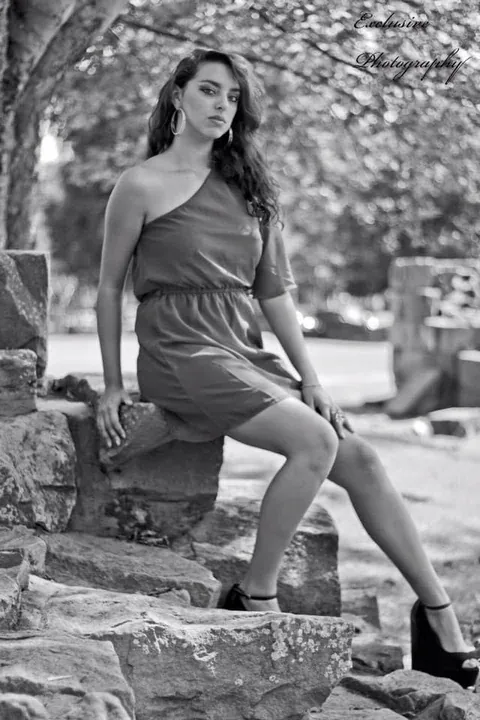 Black and white portrait of a woman seated on stone outdoors