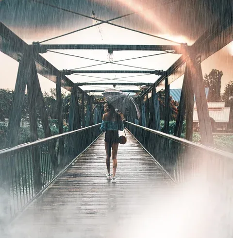 Woman with an umbrella on a bridge, with stylized rain and light
