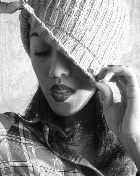 Black and white close-up portrait beneath a knitted hat